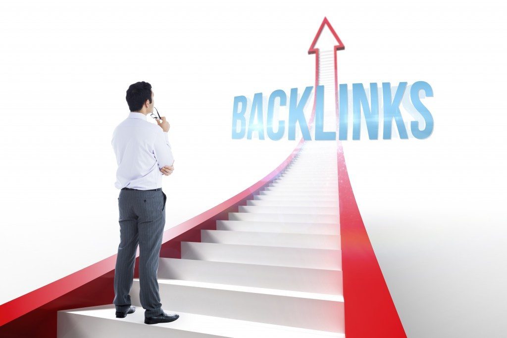 The word backlinks and businessman holding glasses against red arrow with steps graphic