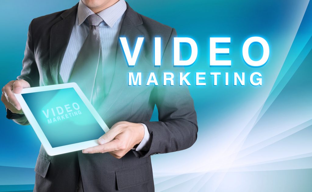 businessman holding tablet with VIDEO MARKETING word with abstract background for Business
