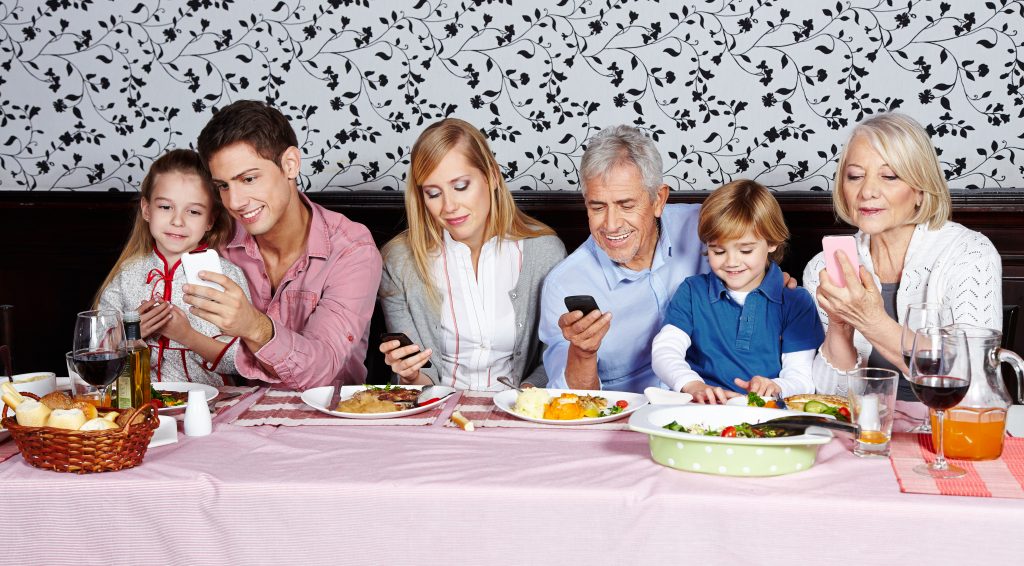 Family looking at their smartphones at the dinner table