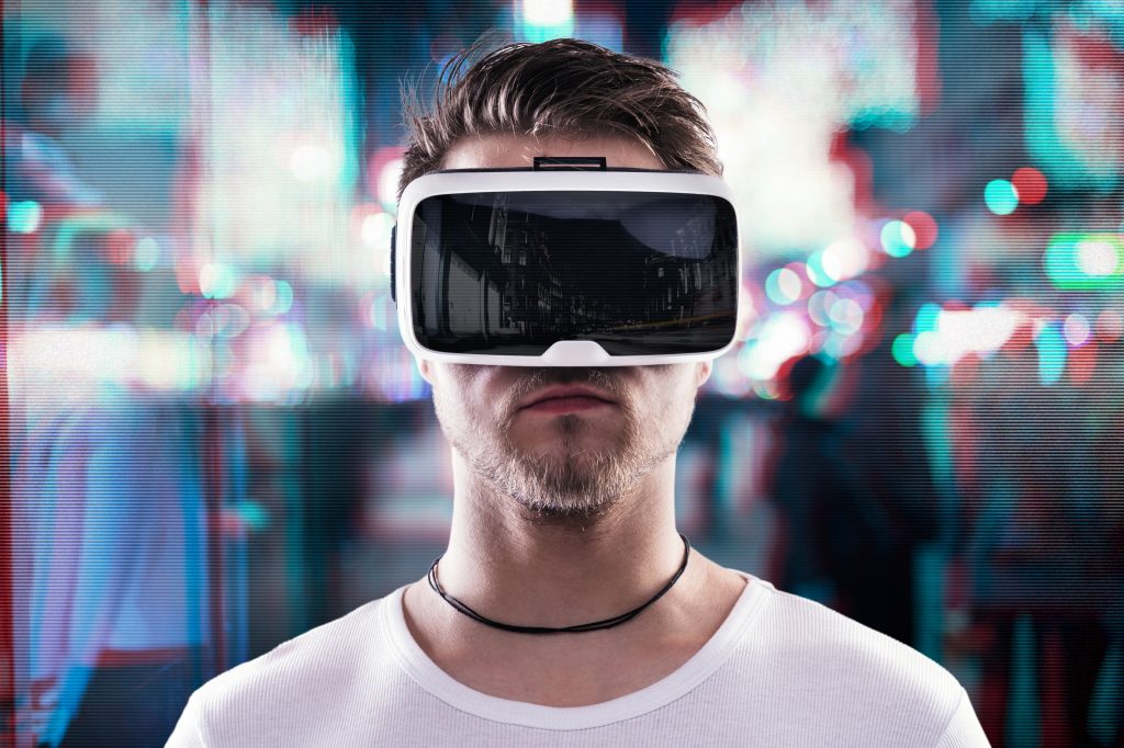 Man wearing virtual reality goggles against illuminated night city