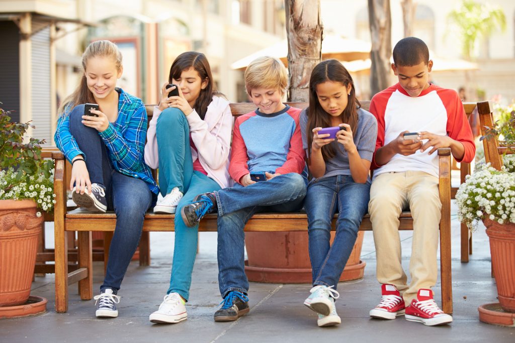 42310004 - group of children sitting in mall using mobile phones