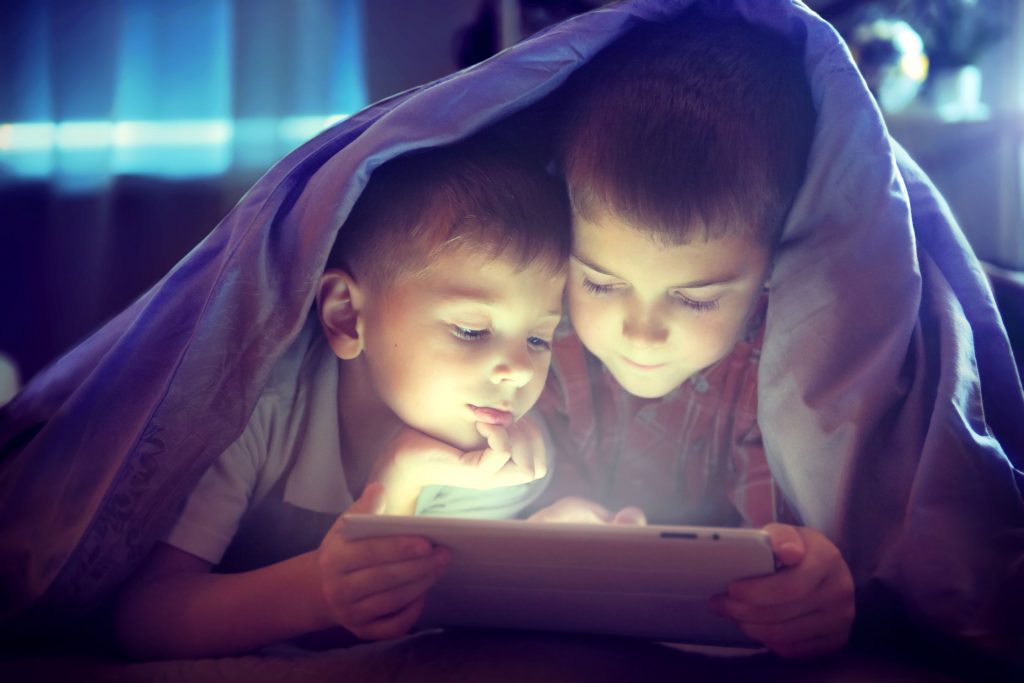 47801825 - two kids using tablet pc under blanket at night