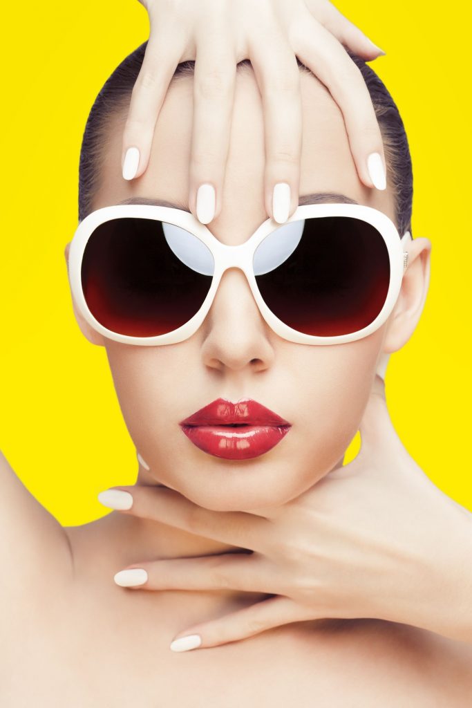 11321175 - closeup portrait of young gorgeous caucasian woman wearing sunglasses, over yellow background