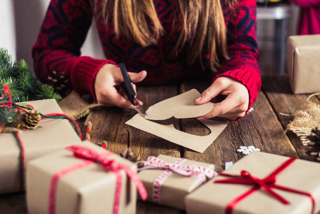 49077948 - male hands wrapping xmas gifts into paper and tying them up with red threads